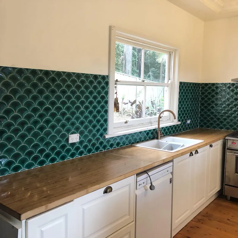 Kitchen splashback with emerald fish-scale tiles and timber benchtop