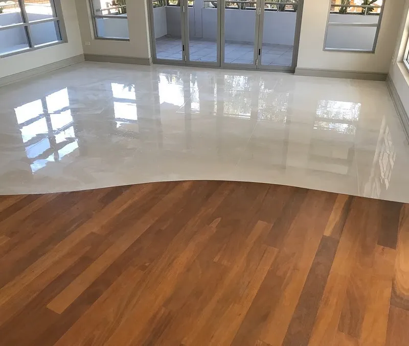 Large format polished marble-look floor tiles with curved transition to timber