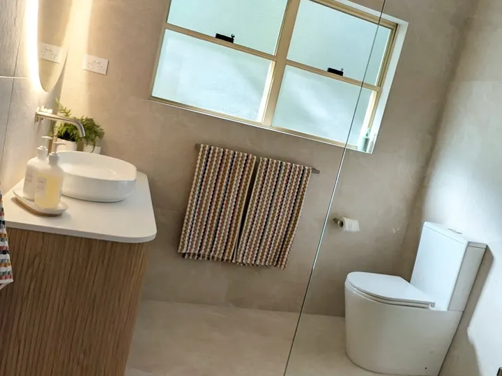 Bathroom renovation featuring large format stone floor tiles and floating timber vanity